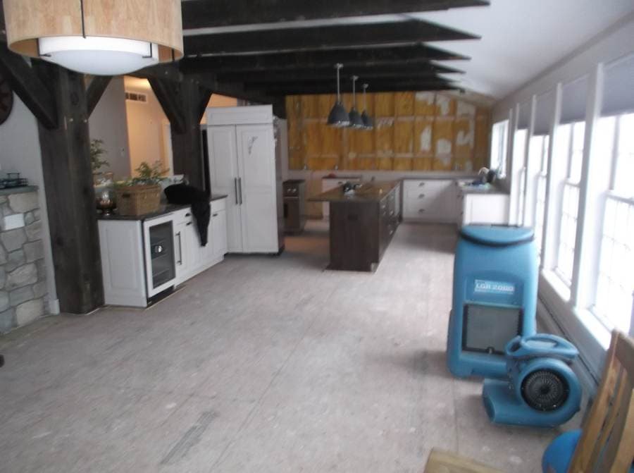 Beamed kitchen mid-mitigation with drying equipment running and walls opened to insulation