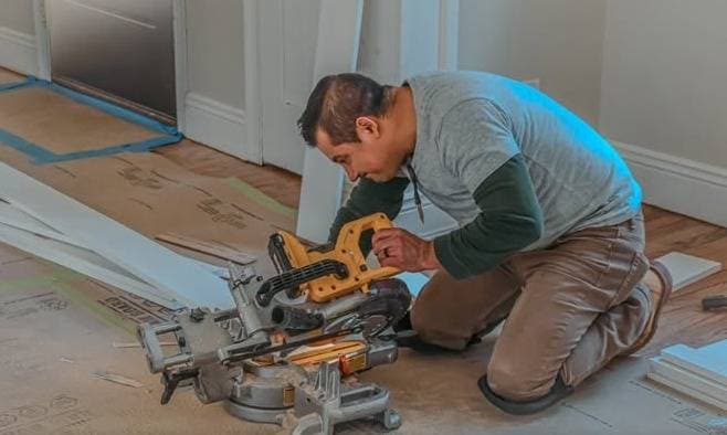 W&K carpenter cutting trim at a miter saw with floor protection in place